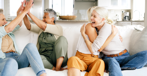 Blije vrouwen op een bank die elkaar omhelzen en een high five geven